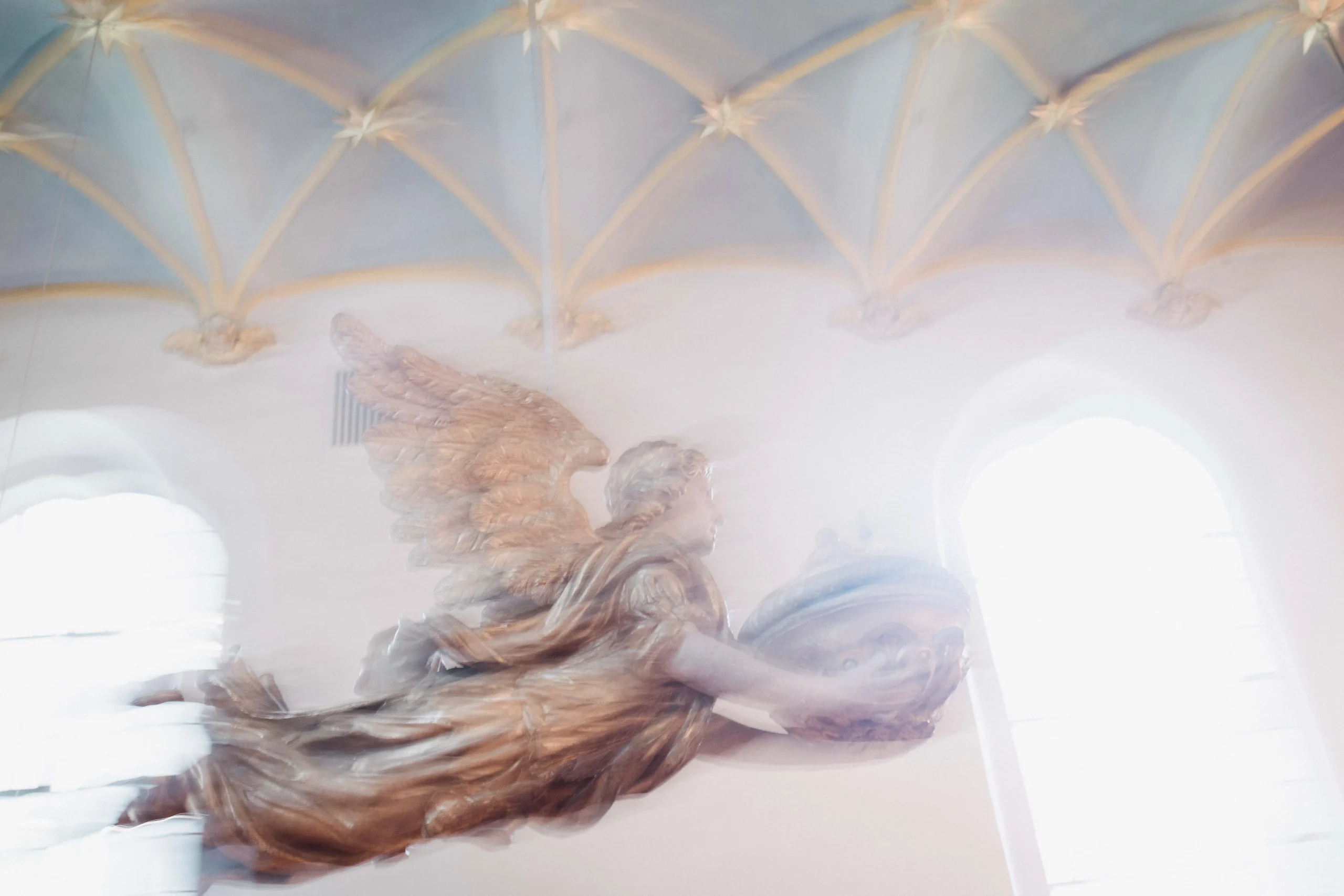 Eine bewegungsunscharfe Figur unter heller Kirchenarchitektur.