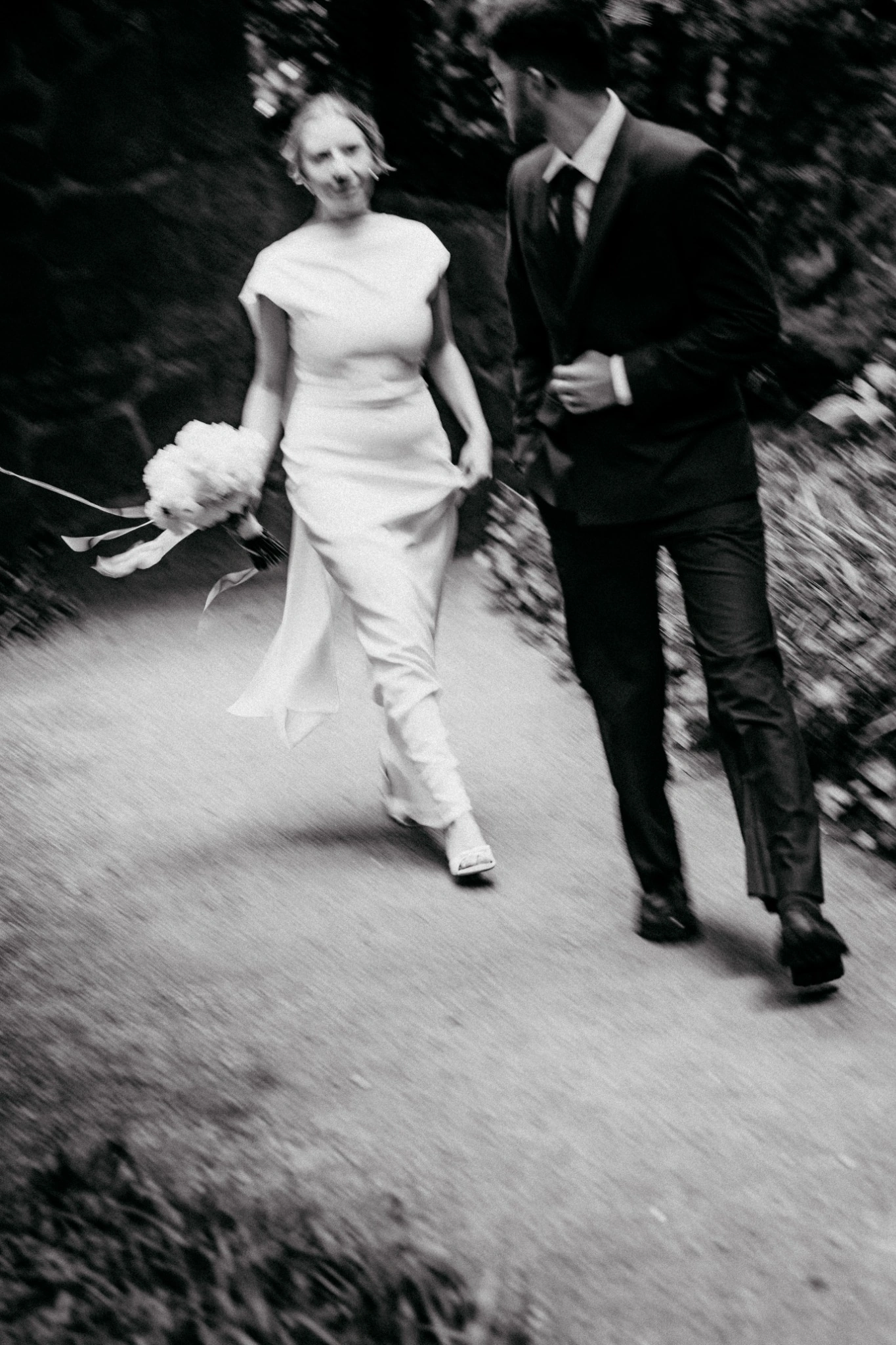 Emi und Merle in Bewegung auf einem Weg. Bewusst unscharfe Schwarz-Weiß-Fotografie.