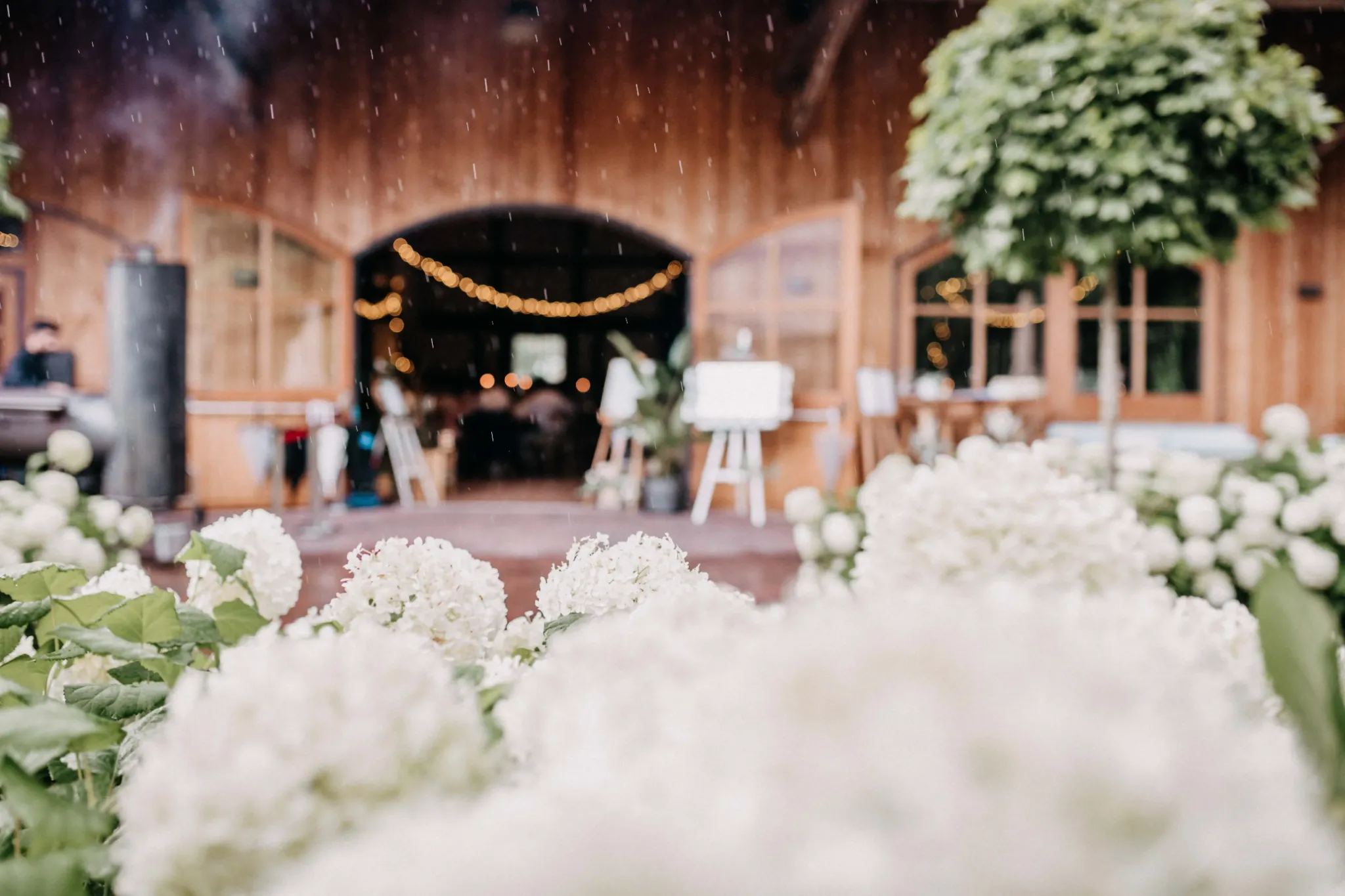 Blumenschmuck vor einer hölzernen Hochzeitslocation.